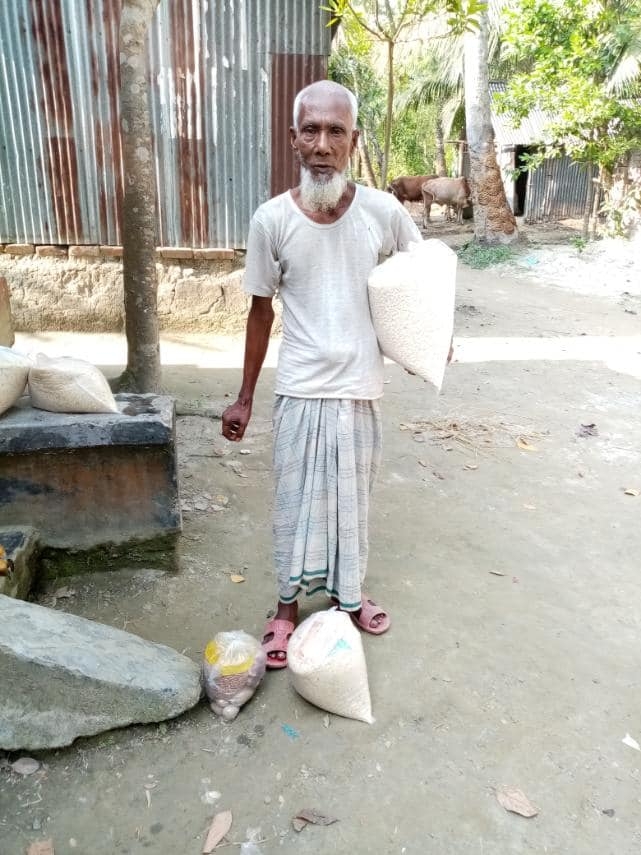 A recipient standing beside food packages
