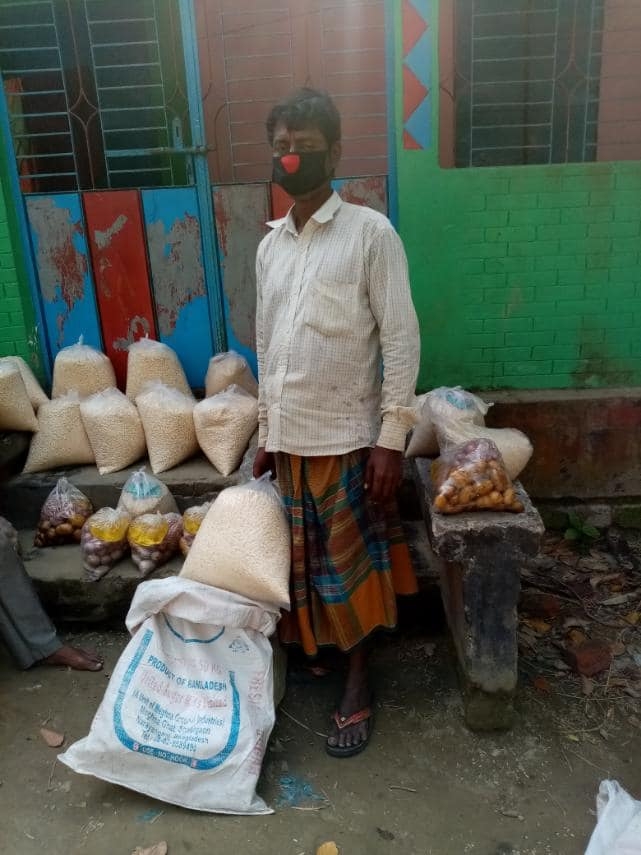 A community member beside prepared food supplies